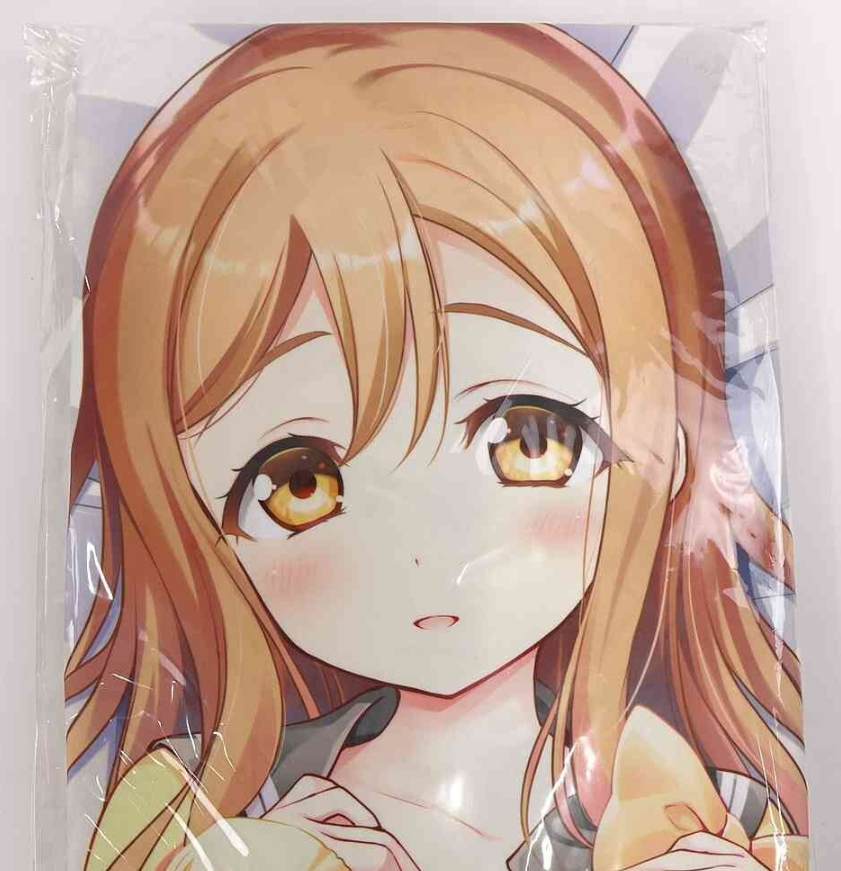 Close-up of an anime-style girl with orange hair and amber eyes, lightly blushing, holding a pastry in her hand inside plastic packaging.