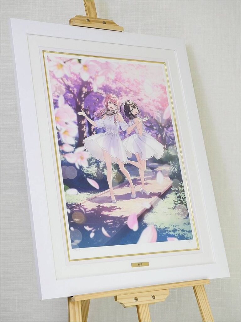Framed anime-style illustration of two girls in white dresses dancing on a wooden bridge under pink blossom trees on an easel surface.